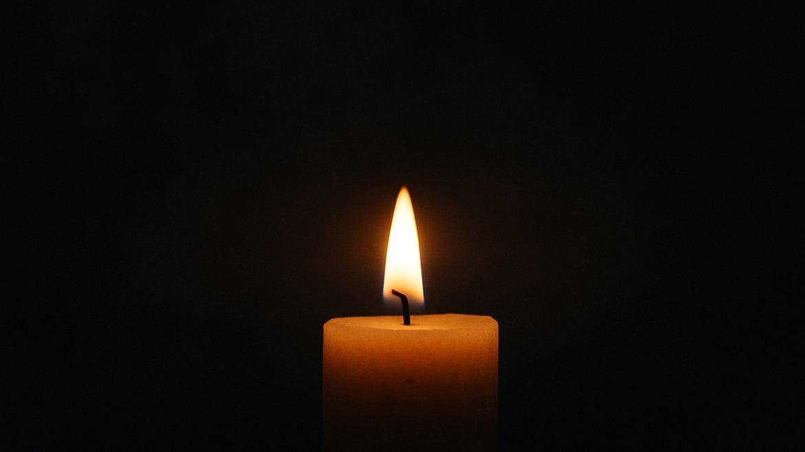 A single candle glowing in darkness, symbolizing hope in heavy times.